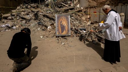 El sacerdote Nelson Giraldo Mejía y un feligrés oran durante una procesión con la Virgen de la Pobreza