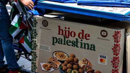Fadi Abed empuja su triciclo mientras se dirige a instalar su puesto de comida "Hijo de Palestina"