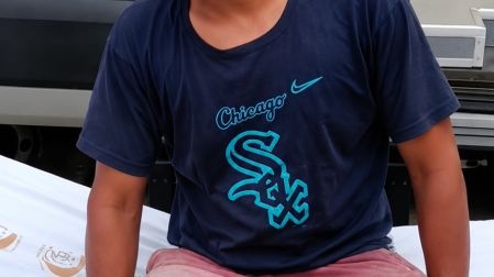 José Luis Portela, pescador joven con camiseta oscura, sentado sobre una camilla médica tras ser valorado por elementos de la Marina.