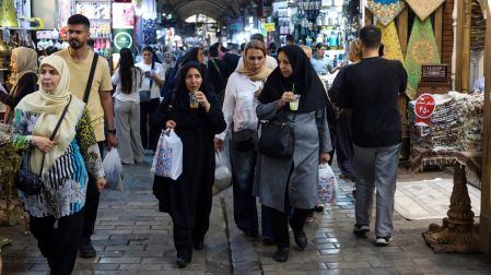 Personas caminan frente a las tiendas y observan mercancías en el Gran Bazar de Teherán