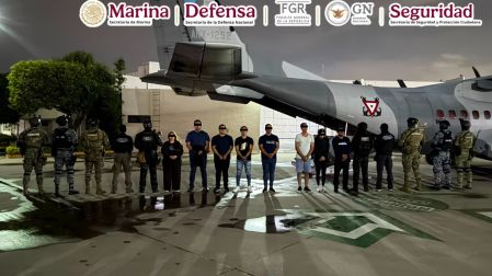 Fuerzas federales de México custodian a un grupo de presuntos integrantes del CJNG frente a un avión de la Armada durante su traslado nocturno.