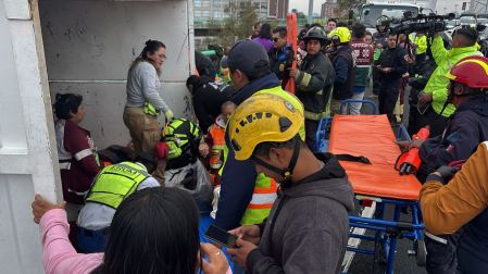 Paramédicos y rescatistas brindando primeros auxilios a trabajadores de limpia lesionados dentro de la caja de una camioneta accidentada.