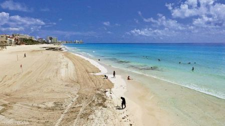 Habitantes de Cancún, retirando sargazo de una playa.