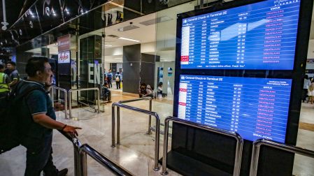 Un pasajero varado consulta el panel de salidas para conocer el estado de los vuelos en el aeropuerto Soekarno-Hatta de Tangerang.
