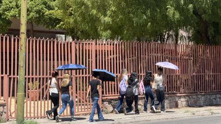 Alumnos usan paraguas para protegerse de los rayos del sol en Baja California