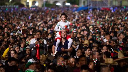 Un padre cargando en hombros a su hija durante la celebración del Grito en el Zócalo de la CDMX.