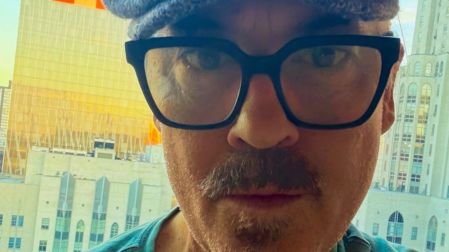 Duncan Sheik con lentes y gorra frente a varios edificios de Nueva York.