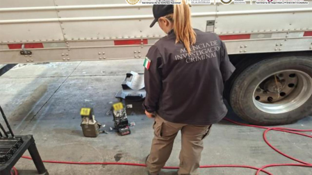 Agente de la Agencia de Investigación Criminal inspeccionando indicios en el suelo junto a la llanta de un tractocamión asegurado