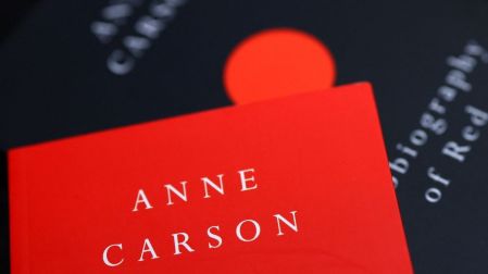 Primer plano de un libro rojo con el nombre de Anne Carson en letras blancas, ganadora del Premio Manuel Acuña 2019.