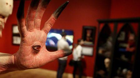 Escultura de una mano monstruosa con un ojo en la palma y dedos alargados, exhibida en una muestra de Guillermo del Toro.