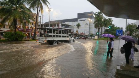 Camión de la Guardia Nacional patrullando sobre una avenida completamente anegada en Acapulco, mientras ciudadanos esperan en la acera con paraguas.