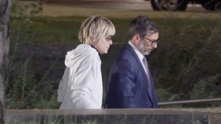 Selma Blair con sudadera blanca, cabello rubio corto y lentes oscuros, caminando junto a un hombre de traje azul.
