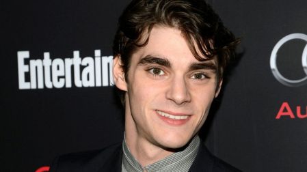 RJ Mitte, actor de Breaking Bad, sonríe con traje negro y camisa gris frente a un fondo con logotipos de Audi y Entertainment Weekly.