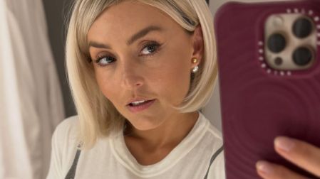Angélique Boyer se toma una selfie frente al espejo con cabello rubio corto, flequillo lateral y camiseta blanca.