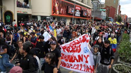 Manifestantes participan en una movilización en Colombia y portan pancartas, banderas y consignas de rechazo a las políticas del Gobierno.
