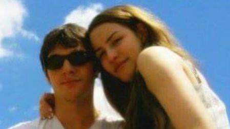 RJ Mitte con lentes de sol y camiseta blanca junto a su exnovia Saint Sasha, abrazados bajo un cielo azul.