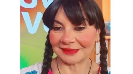 Bettina Salazar, Olga Sana, sonríe con cabello negro en dos trenzas, flequillo, aretes dorados y blusa bordada.