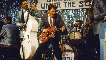 Marty McFly toca una guitarra eléctrica junto a una banda durante el baile escolar de 1955 en Volver al futuro.