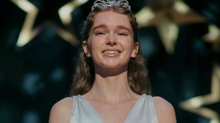 Summer H. Howell como Carrie White, sonriente, con vestido azul claro y tiara plateada durante el baile escolar de Carrie.