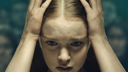 Summer H. Howell como Carrie White, con expresión seria y ambas manos sobre una tiara plateada en la serie Carrie.