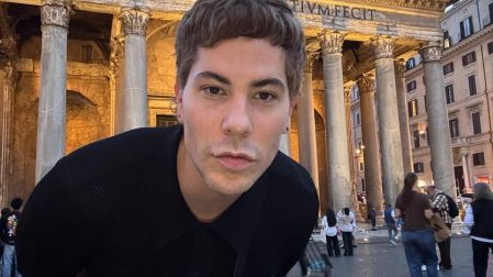 Christian Chávez viste camisa negra y posa frente al Panteón de Agripa en Roma, con columnas antiguas y turistas al fondo.