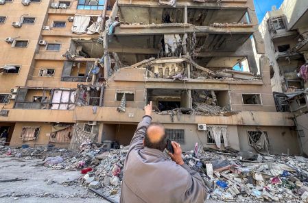 A man points at a building damaged by Israeli strikes, amid escalating hostilities between Israel and Hezbollah, as the U.S.-Israeli conflict with Iran continues, in Beirut's southern suburbs, Lebanon, March 28, 2026. Picture taken with a mobile phone. REUTERS/Stringer     TPX IMAGES OF THE DAY