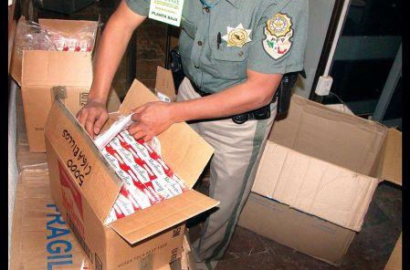 Un policía, con cajas decomisadas de cigarros de contrabando.