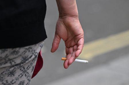 (FILES) A person is seen smoking a cigarette in central London on June 9, 2022. The British Parliament has passed a law aimed at making the UK a progressively tobacco-free country by banning the sale of cigarettes for life to anyone born after 2008  a first in Europe. Here are five things to know about this law, which the government has hailed as "historic" and which advocacy groups have praised as a major turning point. The ban on sales to young people born after 2008 will begin on January 1, 2027, the year they turn 18. (Photo by JUSTIN TALLIS / AFP)