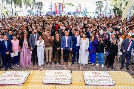 Parejas y autoridades posan durante boda colectiva en Gustavo A. Madero, con asistentes reunidos bajo estructura en evento civil masivo