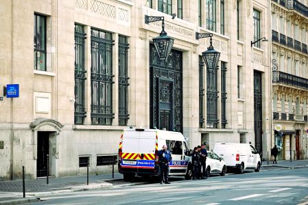 Police officials stand alongside police and private security vehicles outside The Bank of America building in the 8th arrondissement of Paris on March 28, 2026, following an apparent bomb attack attempt. French police stopped an apparent bomb attack outside a US bank in Paris early March 28, 2026, when they arrested a man about to set off a homemade explosive device, sources close to the case told AFP. The incident occurred around 3:30 am (0130 GMT) in front of a Bank of America building in the chic 8th arrondissement, a couple of streets from the Champs-Elysees. (Photo by Sebastien DUPUY / AFP)