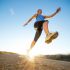 Mujer practicando running al aire libre sobre una avenida, captada desde un ángulo bajo durante una zancada, con luz natural al amanecer, en un entorno urbano asociado a la actividad física y el bienestar.