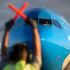 Asistente de vuelo en pista mientras avión aterriza.