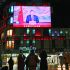 People stand beneath a large screen showing China's President Xi Jinping delivering a speech ahead of the New Year's eve celebrations in Beijing on December 31, 2025. China's President Xi Jinping said on December 31 that "reunification...is unstoppable" as he addressed the nation shortly after Beijing's military announced the end of live-fire drills around Taiwan. (Photo by WANG Zhao / AFP)