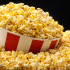 Recipiente con palomitas de maíz amarillas y blancas sobre un fondo oscuro, representación de un snack popular asociado al cine que puede estar contraindicado en ciertos casos médicos como implantes dentales o problemas digestivos.