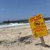 Señal de advertencia por contaminación de aguas residuales en la playa de Imperial Beach, en California, con el muelle al fondo, como consecuencia de descargas de aguas negras que afectan la costa y representan un riesgo a la salud pública.