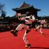 Dos robots humanoides ejecutan una danza sobre un escenario rojo frente a un edificio tradicional en Beijing, mientras el público observa durante las celebraciones del Año Nuevo Lunar 2026, en el Año del Caballo.