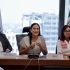 Funcionarias del gobierno federal sentadas en mesa de trabajo durante reunión sobre el Plan de Justicia San Quintín, con banderas institucionales al fondo.