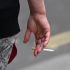 (FILES) A person is seen smoking a cigarette in central London on June 9, 2022. The British Parliament has passed a law aimed at making the UK a progressively tobacco-free country by banning the sale of cigarettes for life to anyone born after 2008  a first in Europe. Here are five things to know about this law, which the government has hailed as "historic" and which advocacy groups have praised as a major turning point. The ban on sales to young people born after 2008 will begin on January 1, 2027, the year they turn 18. (Photo by JUSTIN TALLIS / AFP)