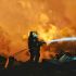 Bombero con manguera combate incendio entre escombros tras explosión en fábrica de fuegos artificiales en Liuyang, Hunan, China.