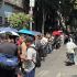 Largas filas de personas esperando pasar por un acceso estrecho hacia el Zócalo de la CDMX, debido a los bloqueos con vallas metálicas de la policía por el plantón de la CNTE.