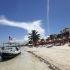 Lancha tradicional anclada en la playa de arena blanca y aguas cristalinas de Mahahual, Quintana Roo, rodeada de palmeras y hoteles boutique.