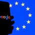 Una persona sostiene un celular con el logo de Google y al fondo la bandera de la UE.