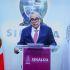Rubén Rocha Moya, Gobernador de Sinaloa, en conferencia de prensa. Viste traje azul, corbata fucsia y gafas.