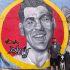 El padre de Daniel Flores posa frente a un mural de su hijo, quien desapareció a la edad de 19 años, en marzo de 2021.