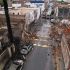 Vista aérea con dron de la destrucción masiva en una calle de Ojocaliente, Zacatecas, tras la explosión de un coche bomba. Se observan edificios colapsados, escombros esparcidos, varios autos calcinados en primer plano y el letrero 'REFACCIONARIA OJOCALIENTE' dañado. Al fondo, vehículos policiales y acordonamiento.