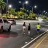 Tres corredores avanzan por una vialidad de Guayaquil de madrugada mientras una camioneta circula detrás del grupo.