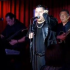 Alejandro Zúñiga interpreta sus canciones durante una presentación en vivo, acompañado por músicos, ante el público y con iluminación escénica.
