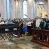 Familiares y asistentes permanecen de pie junto a un féretro durante una ceremonia funeraria dentro de una iglesia.