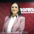 Ariadna Montiel, dirigente de Morena, habla ante dos micrófonos en un podio con el logotipo del partido al fondo.