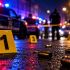 Primer plano de casquillos de bala en el suelo húmedo junto a marcadores de evidencia amarillos, en una escena del crimen nocturna acordonada con presencia de policías y luces de patrullas al fondo.